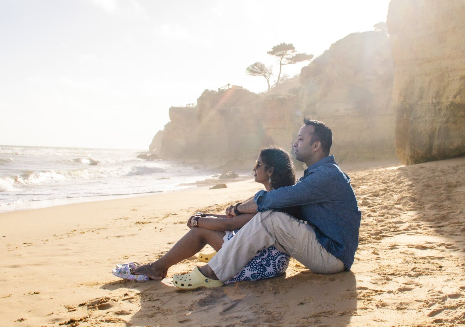 Couple sitting on the beach at golden hour, Algarve